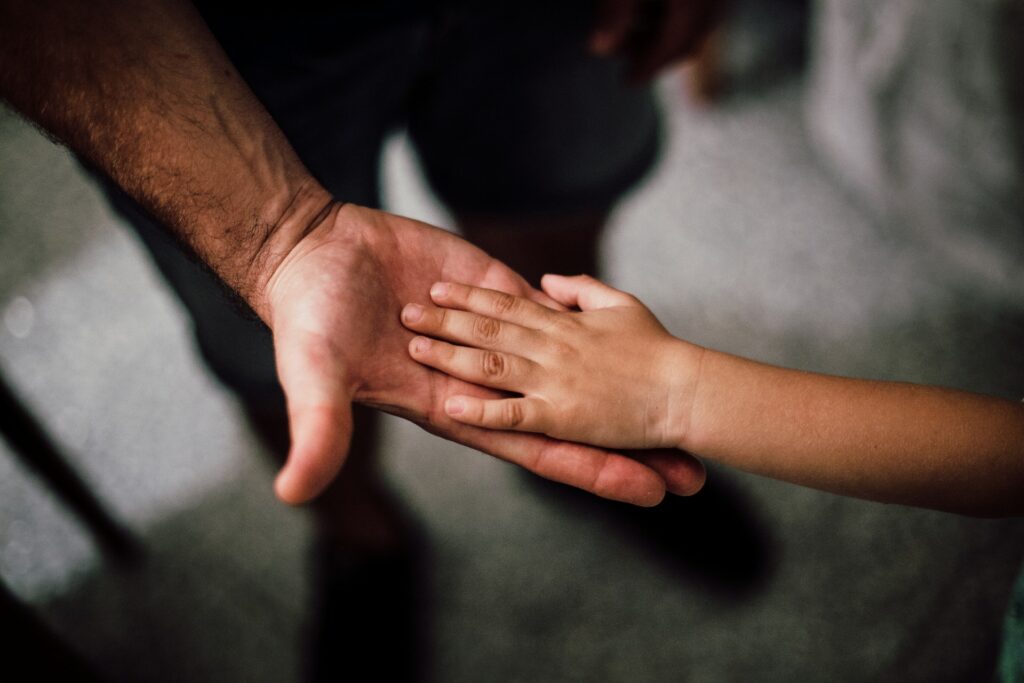 Hand of child reaching to man's hand